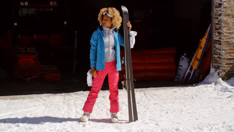 Confident-young-woman-in-snowsuit-with-skis