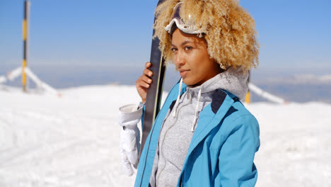 Thoughtful-young-woman-standing-holding-her-skis