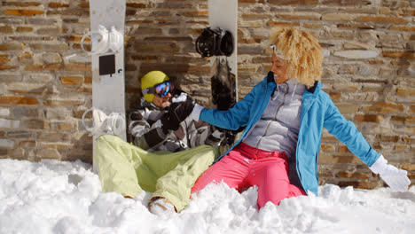 Laughing-woman-sitting-next-to-friend-in-snow
