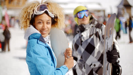 Cute-woman-holding-snowboard-on-ski-slope