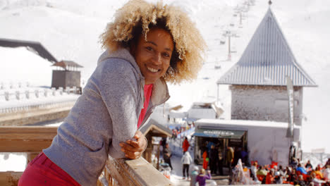 Mujer-Sonriente-Recostada-Sobre-La-Barandilla-En-La-Estación-De-Esquí