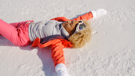 Smiling-woman-in-snowsuit-laying-on-snow