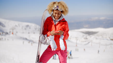 Smiling-skier-check-phone-at-top-of-slope