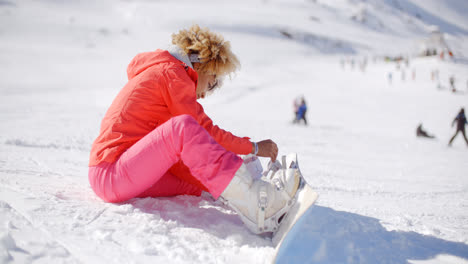 Skier-putting-on-her-snowboard