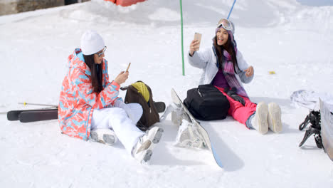 Young-female-friends-relaxing-with-snowboards