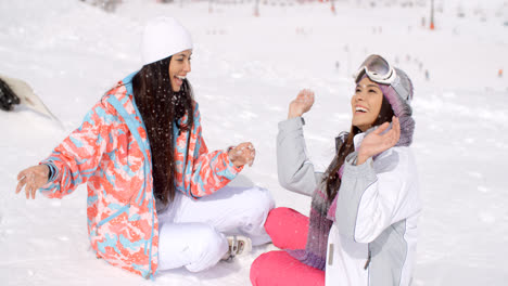 Two-young-female-friends-chatting-in-the-snow