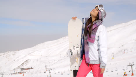 Smiling-gorgeous-woman-posing-with-her-snowboard