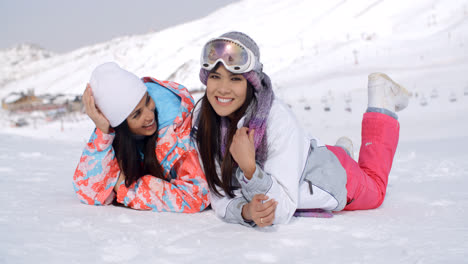 Giggling-twins-laying-down-at-ski-slope