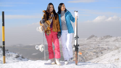 Two-female-snowboarders-standing-on-a-mountain