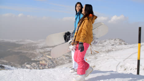 Two-women-carrying-their-snowboards-on-a-mountain