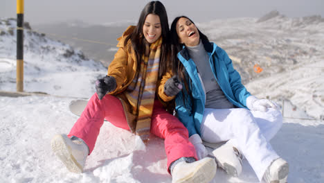 Two-young-female-snowboarders-enjoying-a-chat