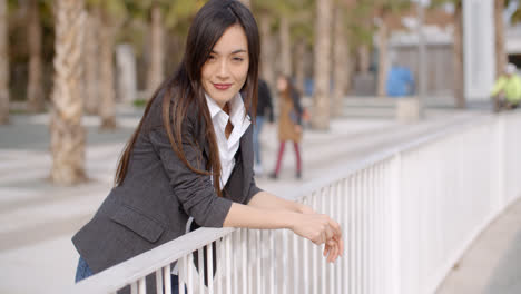 Relaxed-thoughtful-young-woman-leaning-on-railings
