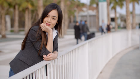 Young-thoughtful-woman-leaning-on-a-railing