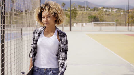 Junge-Frau-Mit-Skateboard-Posiert-Am-Ballplatz