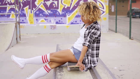 Trendy-young-woman-sitting-on-a-skateboard