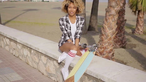 Cute-teenager-sitting-on-ledge-with-skateboard
