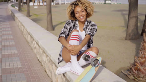 Cute-teenager-sitting-on-ledge-with-skateboard
