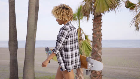 Junge-Frau-Am-Strand-Mit-Ihrem-Skateboard