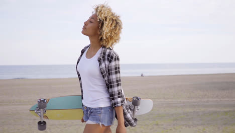 Sexy-young-woman-carrying-a-skateboard-at-a-beach