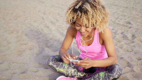 Woman-sitting-at-beach-listening-to-music