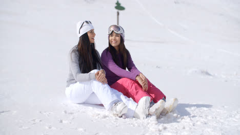 Two-Friends-Sitting-Together-on-Sunny-Ski-Hill