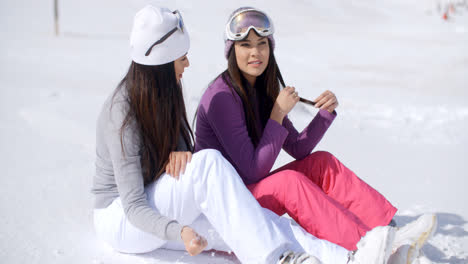 Two-young-women-friends-relaxing-in-the-snow