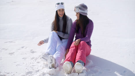 Dos-Mujeres-Jóvenes-Sentadas-Charlando-En-La-Nieve