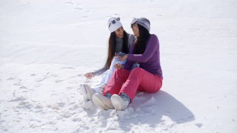 Two-young-women-sitting-chatting-in-the-snow