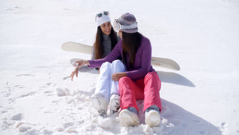 Two-young-women-sitting-chatting-in-the-snow