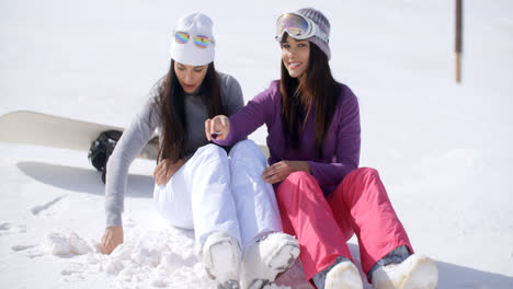 Two-young-women-sitting-waiting-in-the-snow