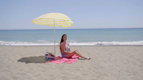 Einsame-Frau-Sitzt-Am-Strand-Unter-Sonnenschirm