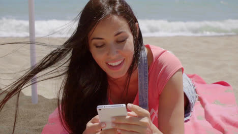 Mujer-Recostada-En-La-Playa-Usando-Teléfono-Celular