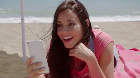 Laughing-woman-using-phone-at-beach