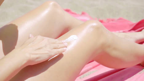 Young-woman-applying-sunscreen-to-her-legs