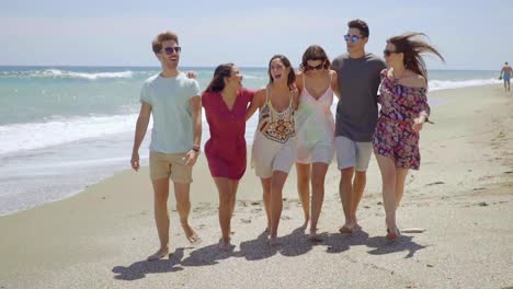 Happy-group-of-young-students-walking-on-a-beach
