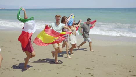 Group-of-Friends-with-Flags-Walking-on-Sunny-Beach