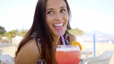 Happy-vivacious-woman-enjoying-a-cocktail