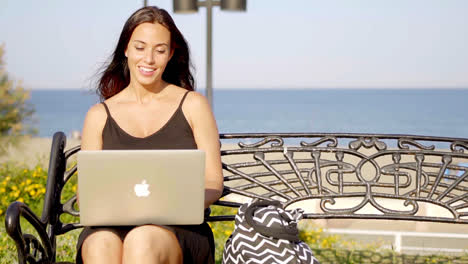 Attractive-woman-typing-on-her-laptop-outdoors