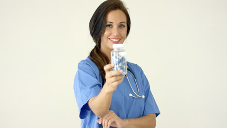 Young-brown-haired-doctor-in-scrubs-holds-bottle