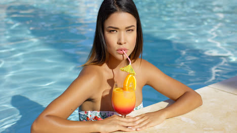 Serious-young-woman-sipping-an-orange-rum-cocktail