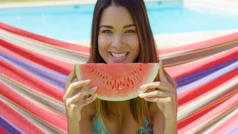 Smiling-young-woman-holding-one-watermelon-slice