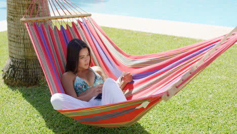 Single-woman-in-bikini-reading-a-book-in-hammock