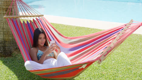 Woman-laying-down-in-hammock-while-using-phone