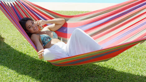 Woman-talking-on-phone-while-relaxing-in-hammock