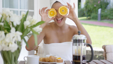 Playful-young-woman-holding-oranges-to-her-eyes