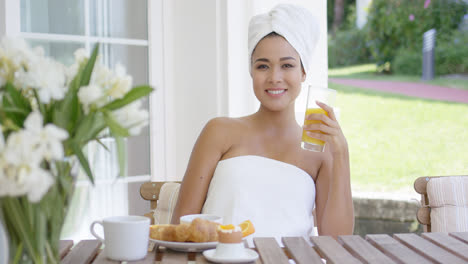 Smiling-woman-wrapped-in-towel-having-breakfast
