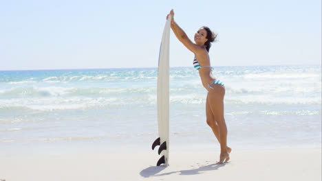 Bathing-beauty-holds-surfboard-and-smiles