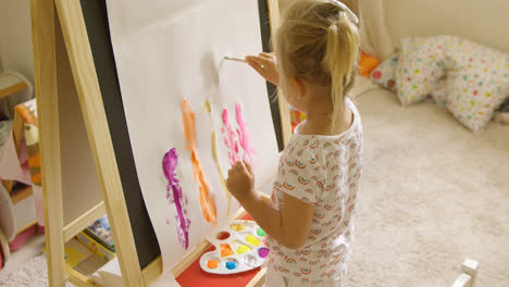 Little-girl-standing-painting-at-an-easel