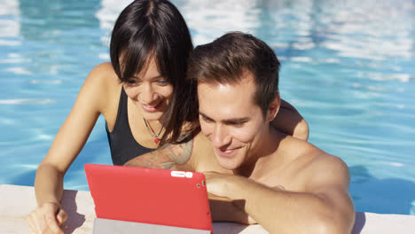 Smiling-couple-in-swimming-pool-use-digital-device