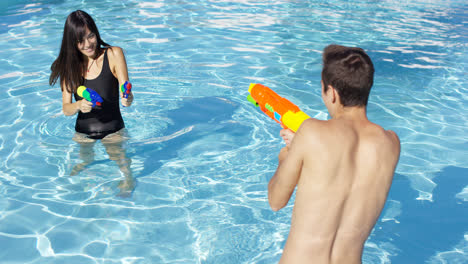 Cute-couple-shooting-off-water-pistols-in-pool